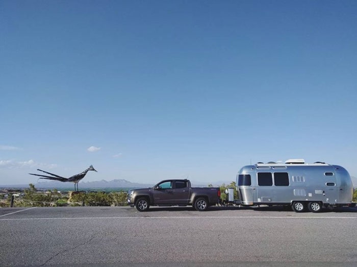 Roadrunner sculpture next to truck towing an Airstream travel trailer